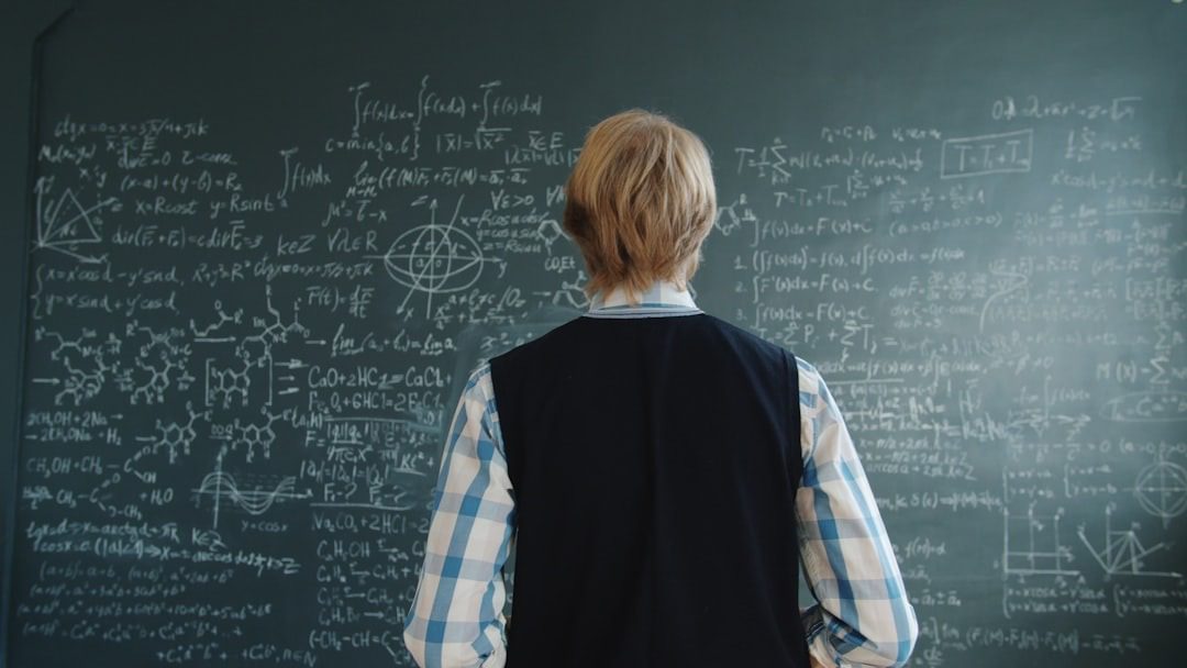 Student studying complex math and science formulas on a blackboard.