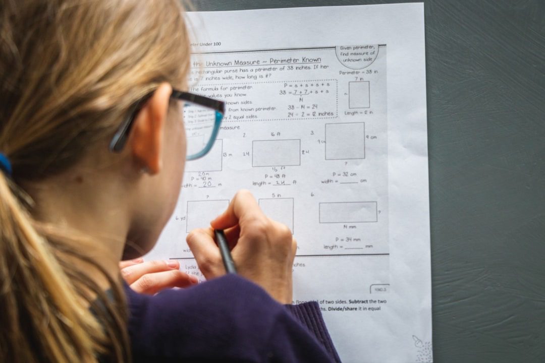 Person with glasses working on a math worksheet.